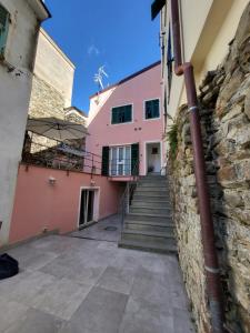 a pink house with a stone wall and stairs at Residenza Solferino in Corniglia