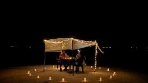 dos personas sentadas en una mesa bajo una tienda con luces en Daisy Cottage Dhangethi, en Dhangethi