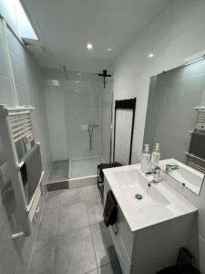 een witte badkamer met een wastafel en een douche bij L'amiénoise proche zenith stade cathédrale in Amiens