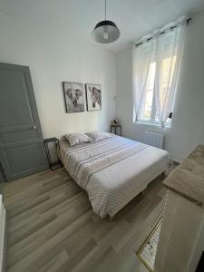een witte slaapkamer met een bed en een raam bij L'amiénoise proche zenith stade cathédrale in Amiens