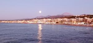 a beach with buildings and the moon in the sky at Sunny Beach Apartments in Rethymno Town