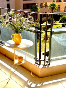 eine Vase mit Blumen auf einem Tisch auf einem Balkon in der Unterkunft Allées Provençales in Aix-en-Provence