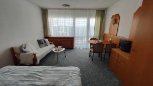 a hotel room with a bed and a couch and a table at Two Apartaments Almberg - Mitterdorf-Mitterfirmiansreut in Mitterfirmiansreut