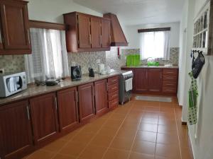 una cucina con armadi in legno e pavimento piastrellato di Casa do Lajedo a Porto Martins