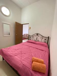 een roze bed met twee oranje handdoeken erop bij Kembara Homestay Four Room in Alor Setar