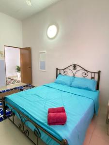 een slaapkamer met een blauw bed en een rood kussen bij Kembara Homestay Four Room in Alor Setar