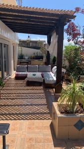 un patio al aire libre con sofá y pérgola en Au Bord du palmier, en Rabat