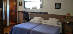 里瓦德奧的住宿－A Cortiña de Cantalarrana，一间卧室配有一张带蓝色毯子的床和窗户。