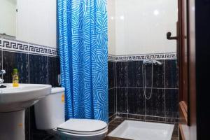 a bathroom with a toilet and a blue shower curtain at Dar Rita in Rabat