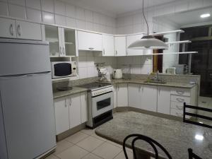 - une cuisine avec des appareils électroménagers blancs et une table dans l'établissement Apt na região central , Completo com 2 camas casal, à Patos de Minas