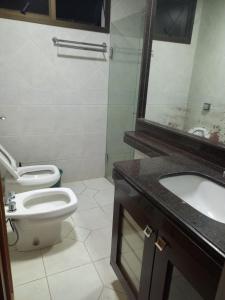 La salle de bains est pourvue de toilettes, d'un lavabo et d'un miroir. dans l'établissement Apt na região central , Completo com 2 camas casal, à Patos de Minas