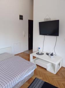 a room with a bed and a table with a tv at Donata in Osijek