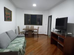 - un salon avec un canapé, une télévision et une table dans l'établissement Apt na região central , Completo com 2 camas casal, à Patos de Minas