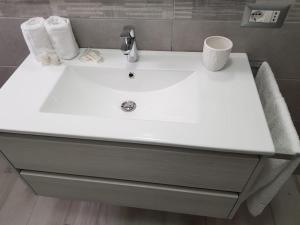 - un lavabo blanc dans la salle de bains avec des serviettes. dans l'établissement Appartamento nuovo, à Lampedusa