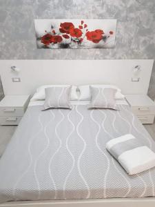 a bedroom with a white bed with red flowers on the wall at Appartamento nuovo in Lampedusa