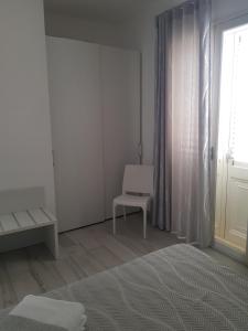 a white room with a bed and a chair at Appartamento nuovo in Lampedusa