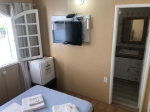 een kamer met een tv op de hoek van een muur bij O Mar Hospedagem - SUÍTES PRIVADAS in Arraial do Cabo