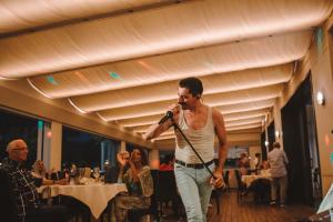 a man singing into a microphone in a restaurant at Hotel Giulia in Lido di Camaiore