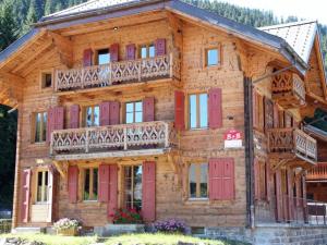 モルジャンにあるChalet Suisse Bed and Breakfastの赤いドアとバルコニー付きの大きな木造家屋