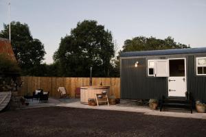 ein schwarzes winziges Haus in einem Hinterhof mit einem Zaun in der Unterkunft Barfield Shepherds Hut in Magherafelt