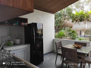 een keuken met een tafel en een zwarte koelkast bij TEGESWOODHOUSE A with WiFi,Ac in Ubud