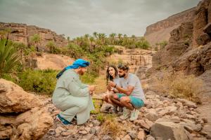 a group of three people sitting on rocks in a canyon at Ouednoujoum Ecolodge & Spa in Ouarzazate