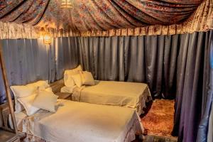 Cette chambre comprend 2 lits et un rideau. dans l'établissement Ouednoujoum Ecolodge & Spa, à Ouarzazate