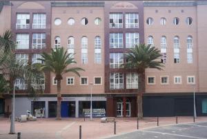 a large building with palm trees in front of it at EL HOGAR DEL MAGEC in Las Palmas de Gran Canaria