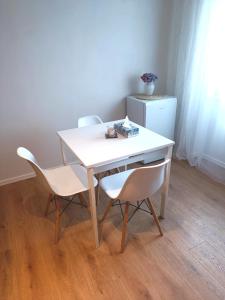 een witte tafel met 2 stoelen en een koelkast bij Zoo Karlovarská Apartment in Pilsen