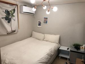 um pequeno quarto com uma cama branca e uma secretária em Rich House Dongdaemun em Seul
