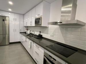 una cocina con armarios blancos y electrodomésticos de acero inoxidable en Royal Pearl Marbella, en Marbella