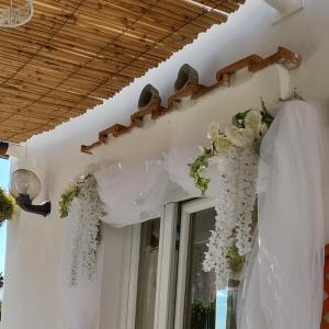 アナカプリにあるラ ネクセッラの白いカーテンと花の窓付きの客室です。