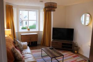 a living room with a couch and a flat screen tv at Cheery Craigie ground floor apartment in Perth