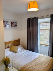 a bedroom with a bed with a black curtain and a window at CityHost Apartments - Newcastle in Elswick