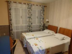2 camas en una habitación pequeña con faldas en Hostal Burbia en Villafranca del Bierzo