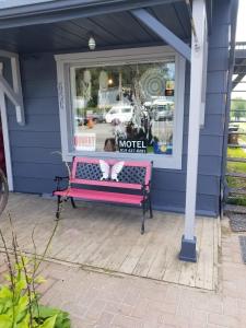 a dog sitting on a bench outside a window at Motel Shantik in Montebello