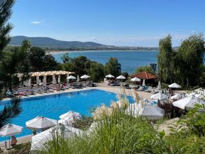 a large swimming pool with umbrellas and the water at Апартамент в Созопол in Sozopol