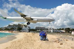an airplane is flying low over a beach with a cart at Fun under the sun! in Cupecoy +21 photos