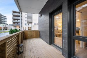 balcón con suelo de madera y puertas de cristal en Apartment in Frogner Lillestrøm - Modern and Central, en Lillestrøm