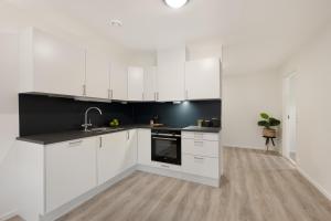 una cocina con armarios blancos y fregadero en Apartment in Frogner Lillestrøm - Modern and Central, en Lillestrøm