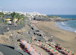 una playa con sombrillas y gente en la playa en Apartamento Belva en Puerto del Carmen
