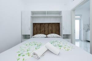 a white bedroom with a large bed with towels on it at Flori Apartments in Ulcinj
