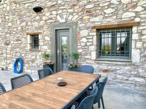 a wooden table and chairs in front of a stone wall at The Backyard in Éva
