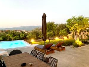 a patio with a pool and chairs and a umbrella at The Backyard in Éva