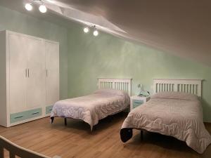 two beds in a room with green walls and wooden floors at Casa Nicolás in La Horra