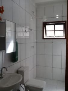 a white bathroom with a toilet and a sink at Linda acomodação a poucos metros da praia in Caraguatatuba +11 photos