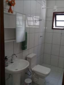 a white bathroom with a toilet and a sink at Linda acomodação a poucos metros da praia in Caraguatatuba