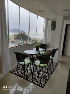 a table and chairs in a room with windows at Ap. frente mar Balneário Camboriú in Balneário Camboriú