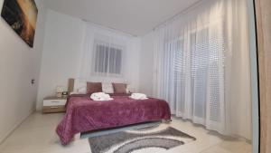 una camera bianca con un letto con una coperta viola di Holiday House Gavran a Vodice