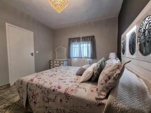 una camera da letto con letto, cuscini e lampadario a braccio di Casa Flora - Casa rural con encanto a El Carpio de Tajo